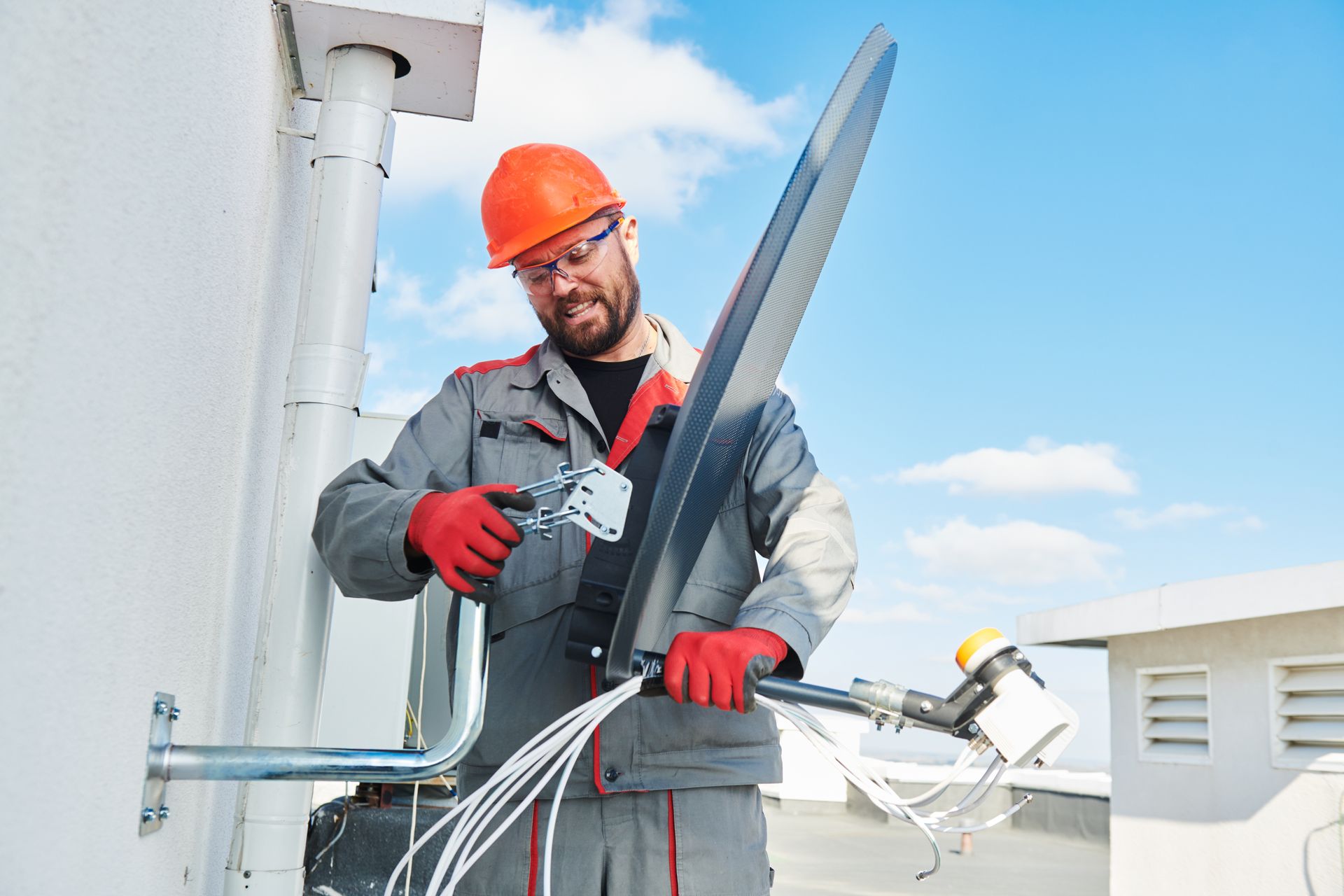Man in hard hat and work suit attaching wind turbine blade on a rooftop.