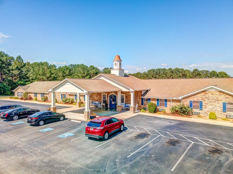 A red car is parked in front of a large building.