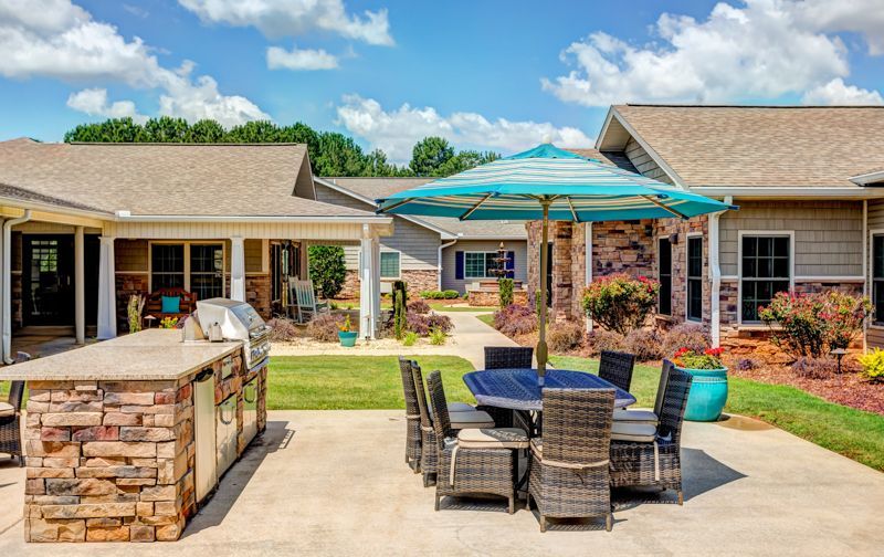 A patio with a table and chairs and an umbrella in front of a house.