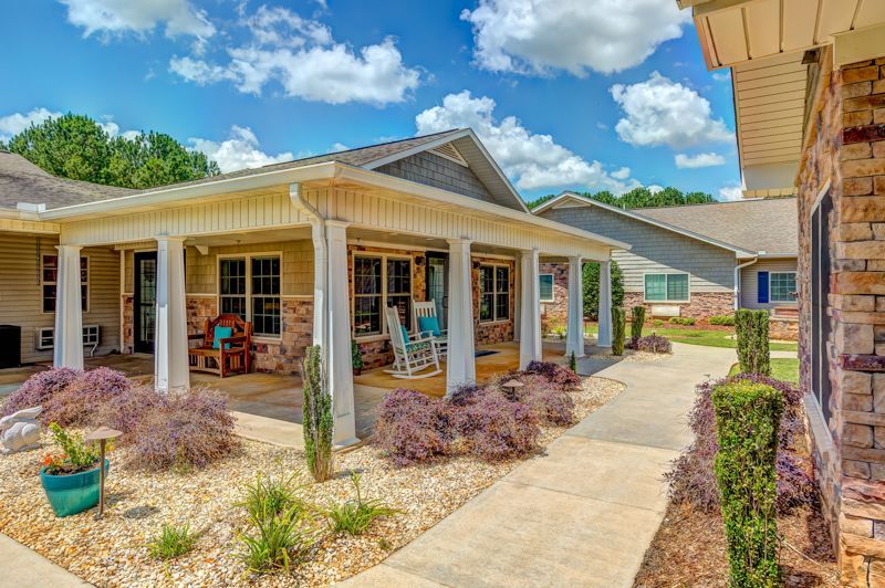 A house with a porch and rocking chairs in front of it.