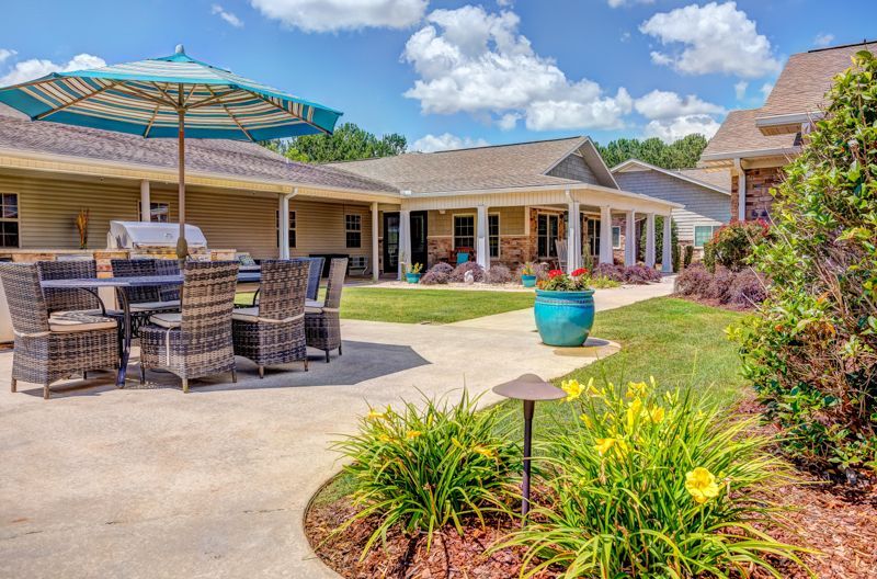 A patio with a table and chairs and an umbrella in front of a house.
