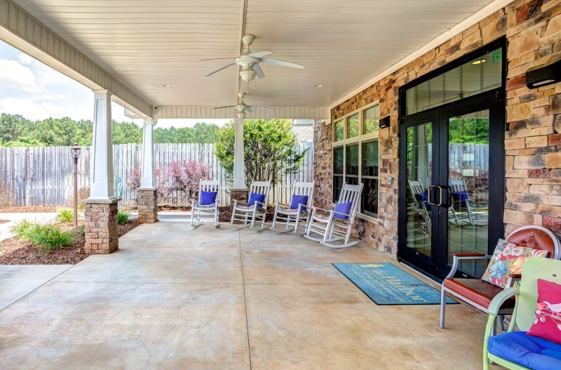 A patio with rocking chairs , a bench , and a ceiling fan.