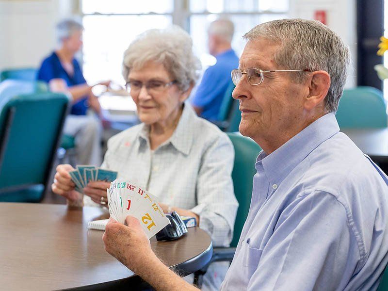 A man and a woman are sitting at a table playing cards.