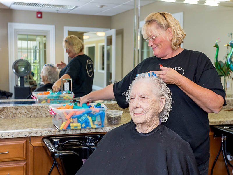 A woman is cutting a woman 's hair in a salon.