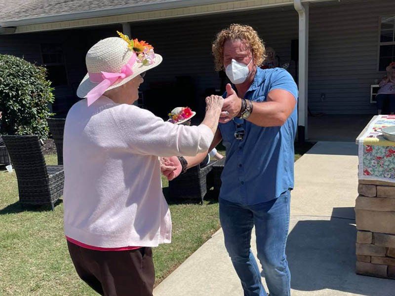 A man wearing a mask is dancing with a woman wearing a pink hat.