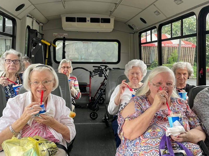 A group of elderly women are sitting on a bus drinking soda.