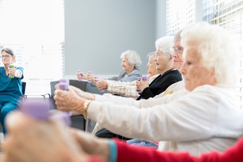 A group of elderly women are doing exercises together in a room.