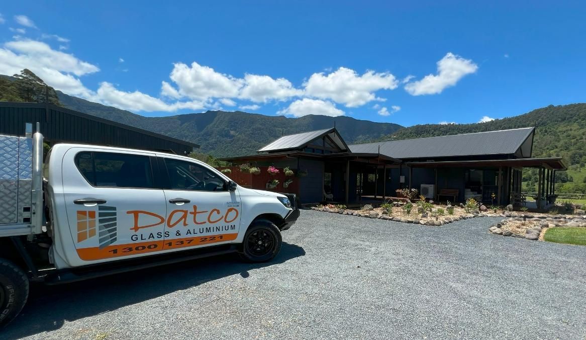 A White Truck Is Parked In Front Of A House With Mountains In The Background — Datco Group In South Murwillumbah, NSW