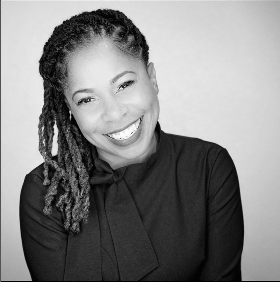 A woman with dreadlocks is smiling in a black and white photo, liz Toussaint, life coach,  life coach training, the coaching guild