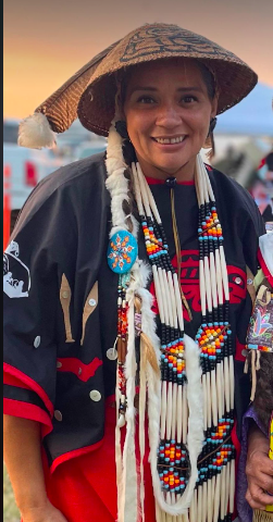 A woman is wearing a native american outfit and a hat.