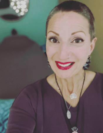 A woman with a shaved head is smiling for the camera