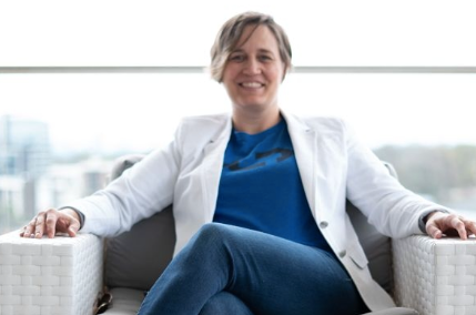 A woman in a blue shirt and white jacket is sitting in a chair