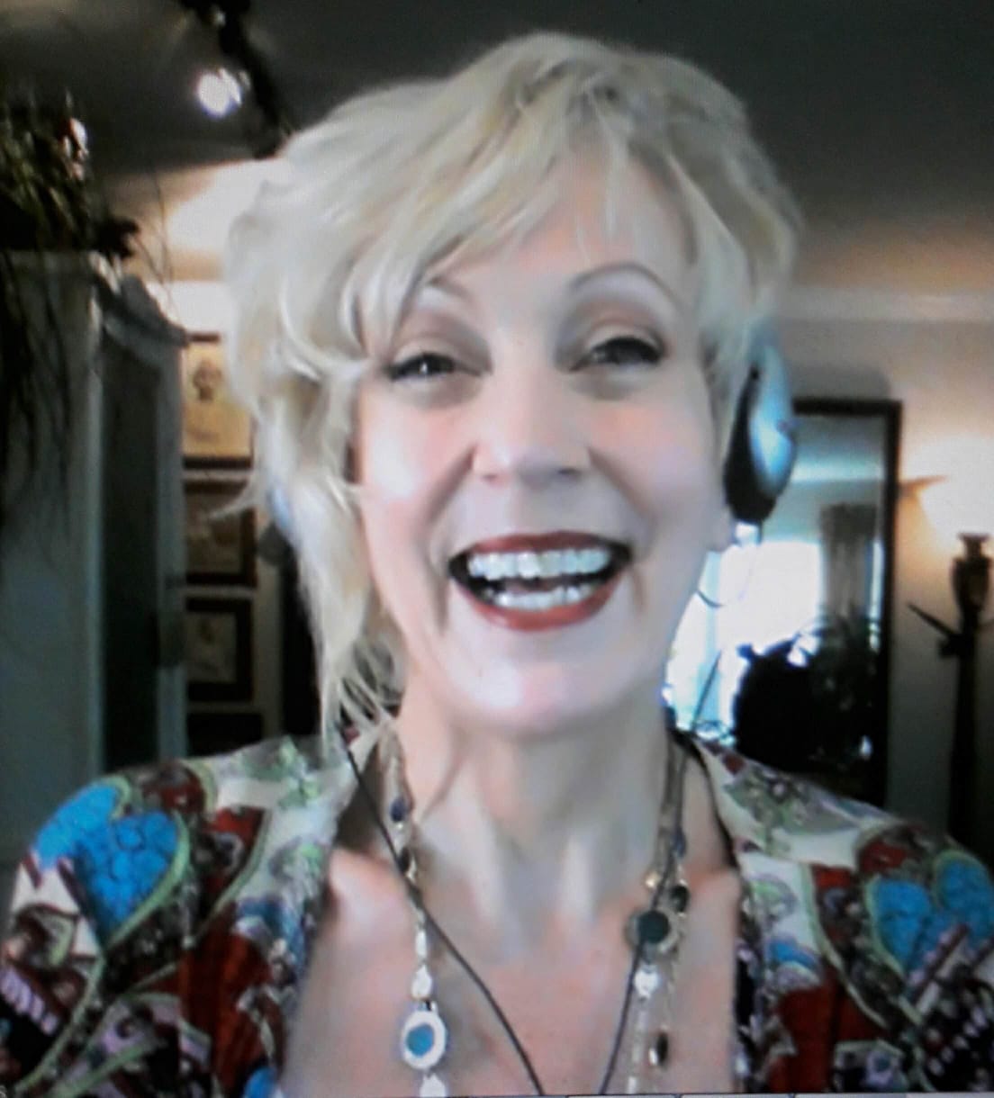 A woman wearing headphones and a necklace smiles for the camera, Jacqueline gates, life coach,  life coach training, the coaching guild