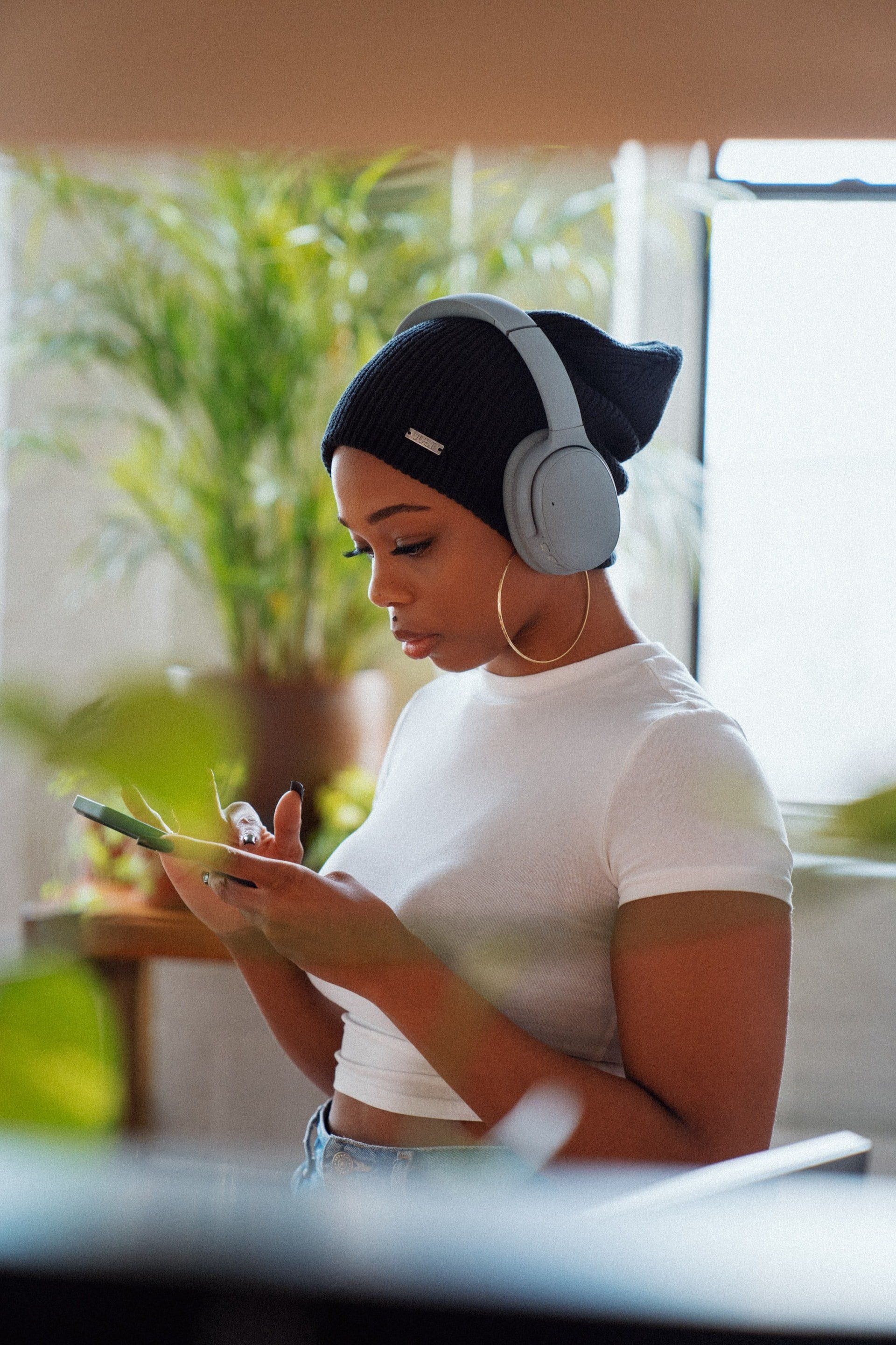 A woman wearing headphones is looking at her phone.