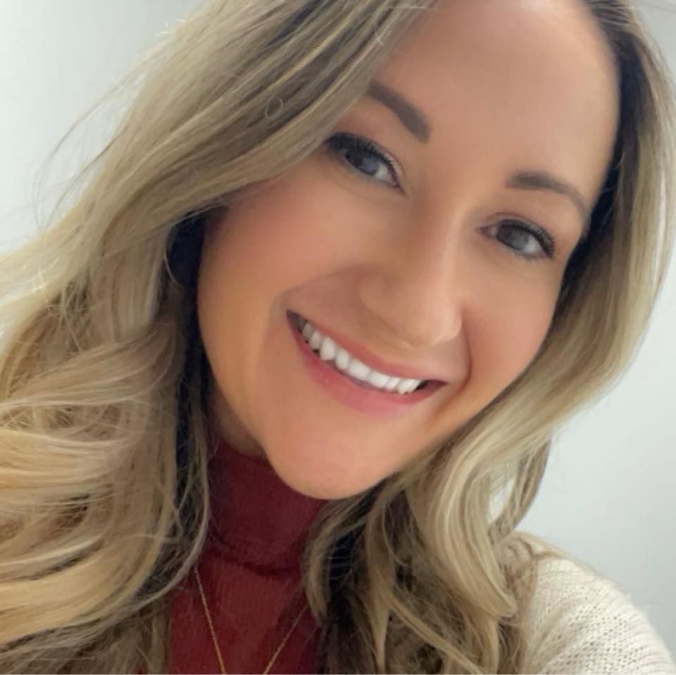 Chris Darr, owner, smiling in a grey and white checkered blazer.