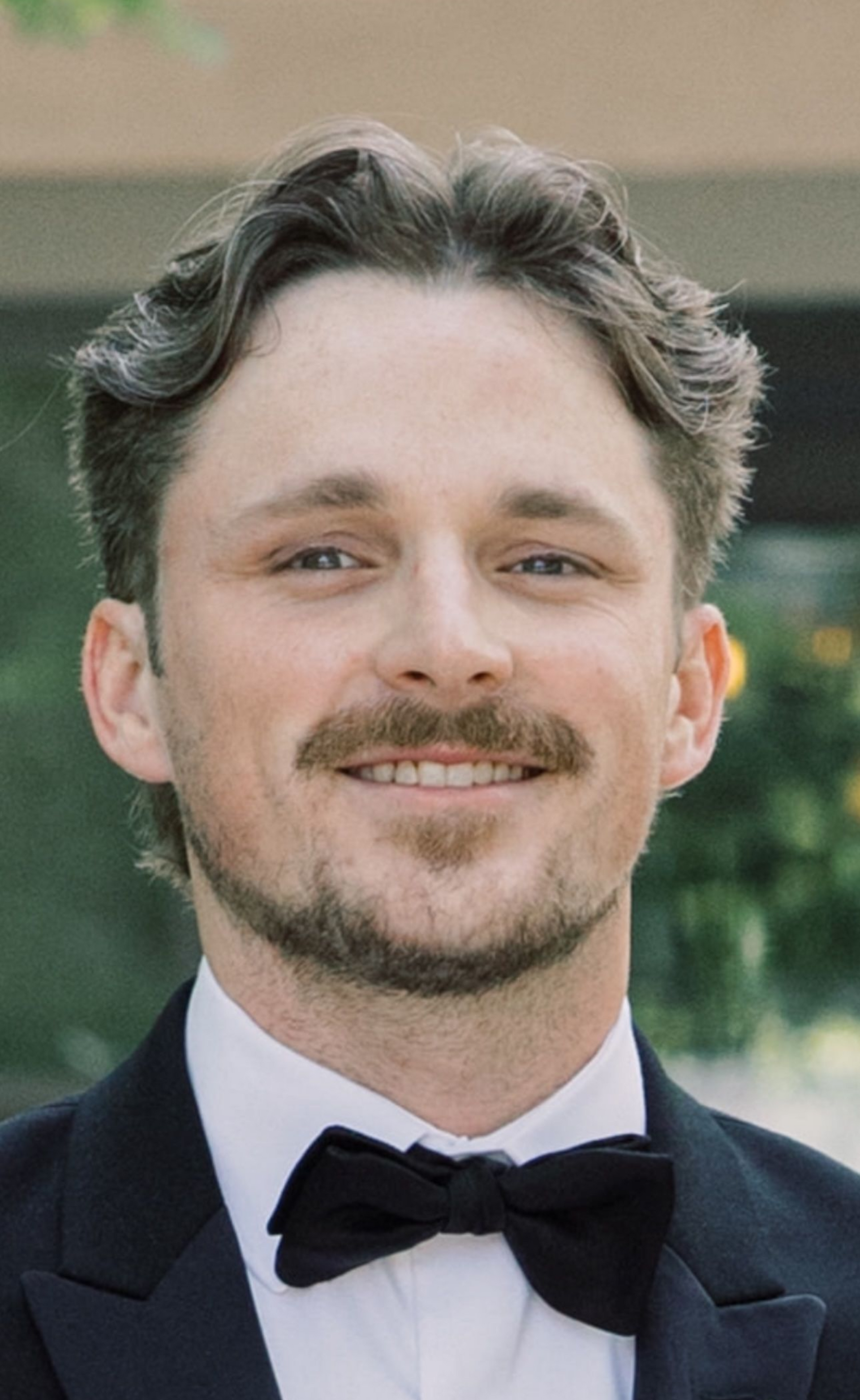 Chris Darr, owner, smiling in a grey and white checkered blazer.