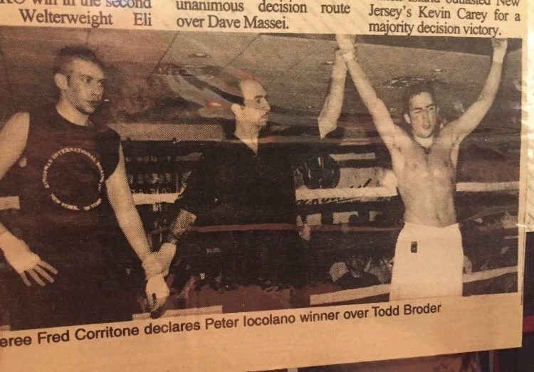 Boxer Peter Iocolano declared winner by referee Fred Corritone over Todd Broder in the ring, hands raised in victory.