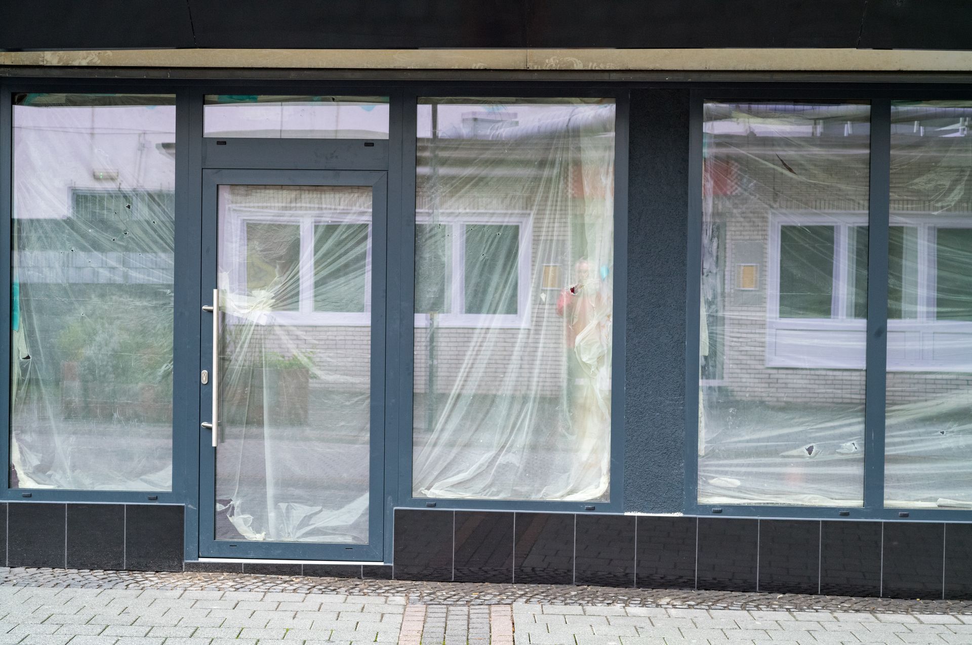 A building with a lot of windows and a door is covered in plastic.
