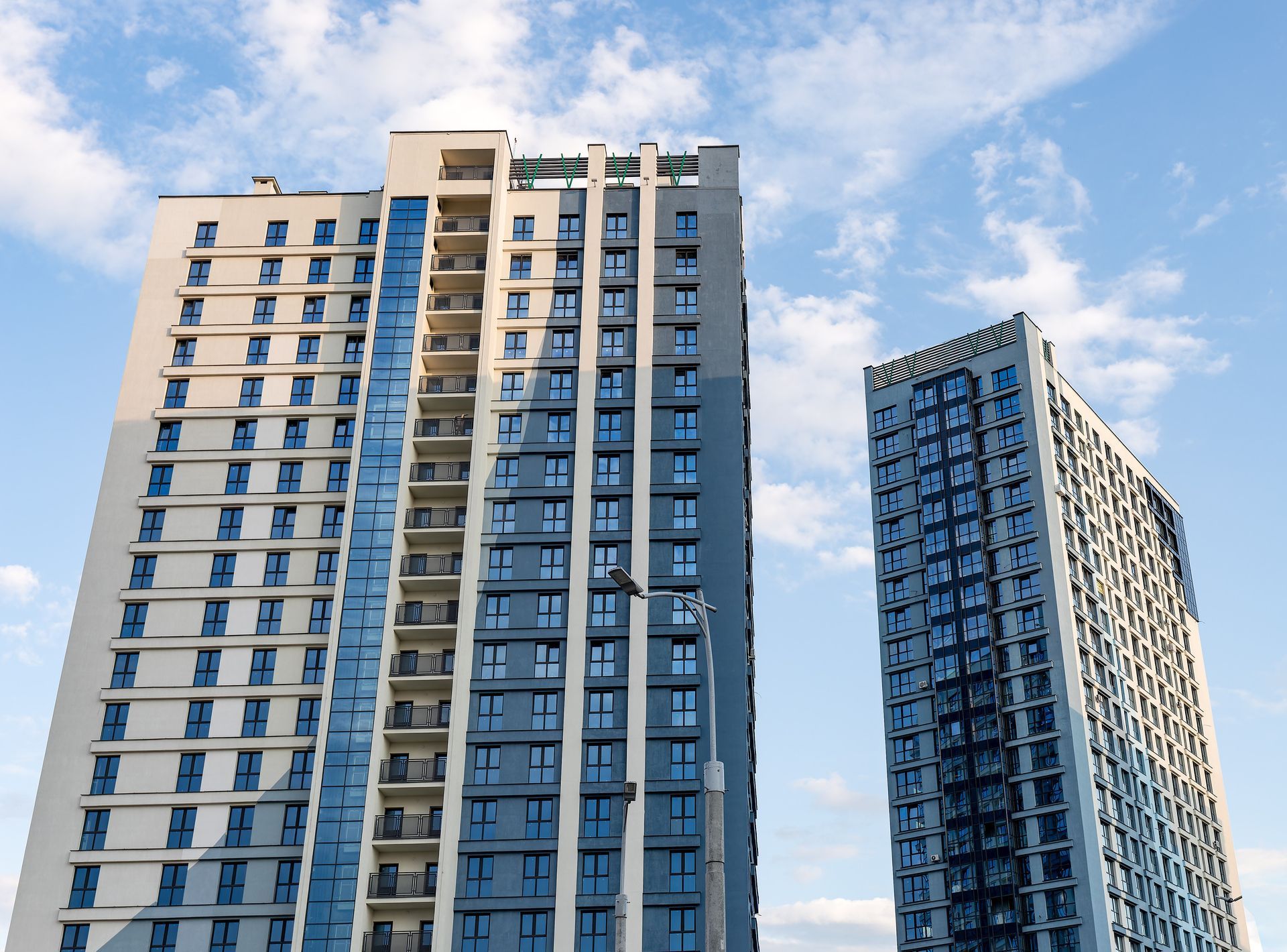 Three tall buildings are against a blue sky with clouds.