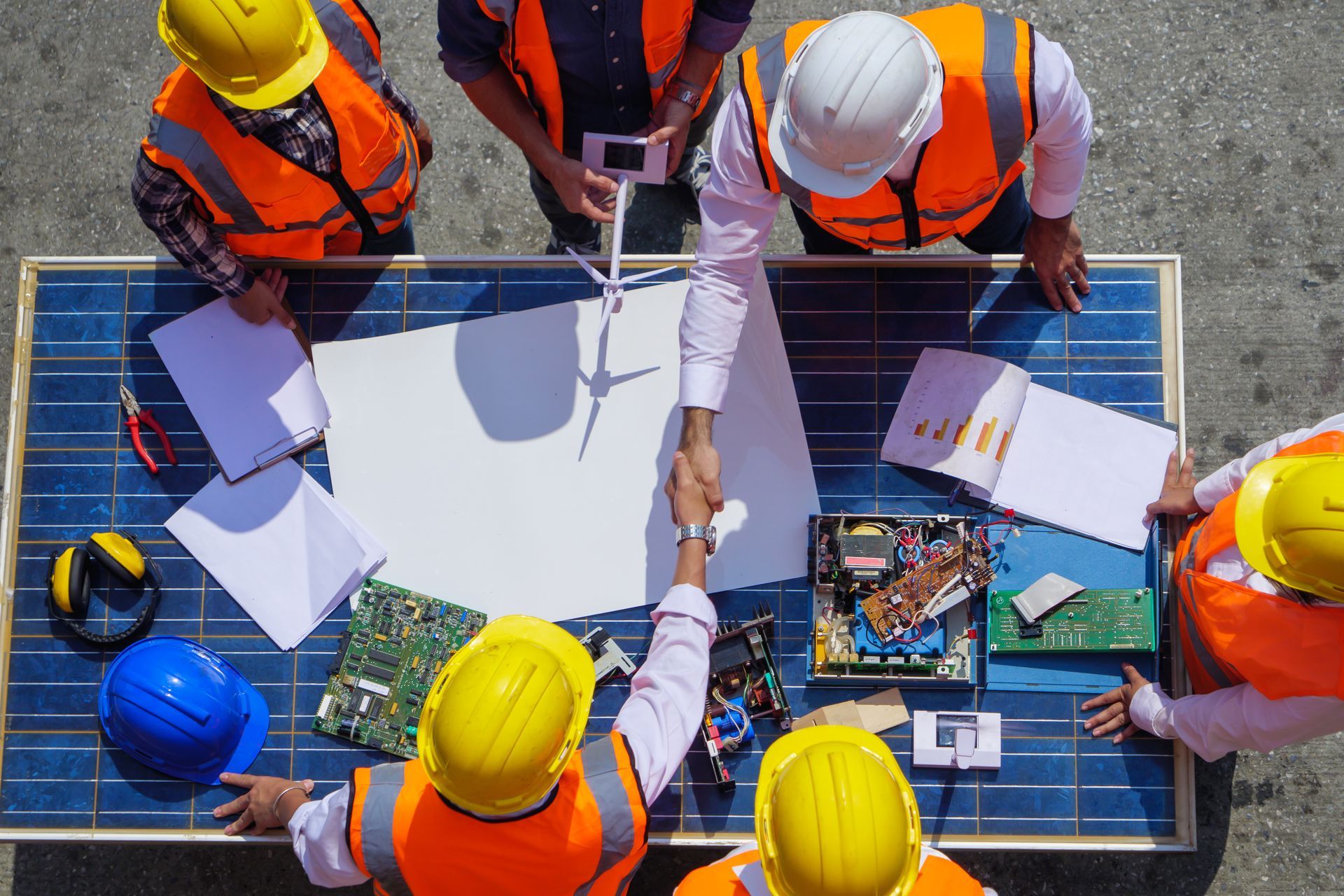 A group of construction workers are shaking hands over a solar panel.