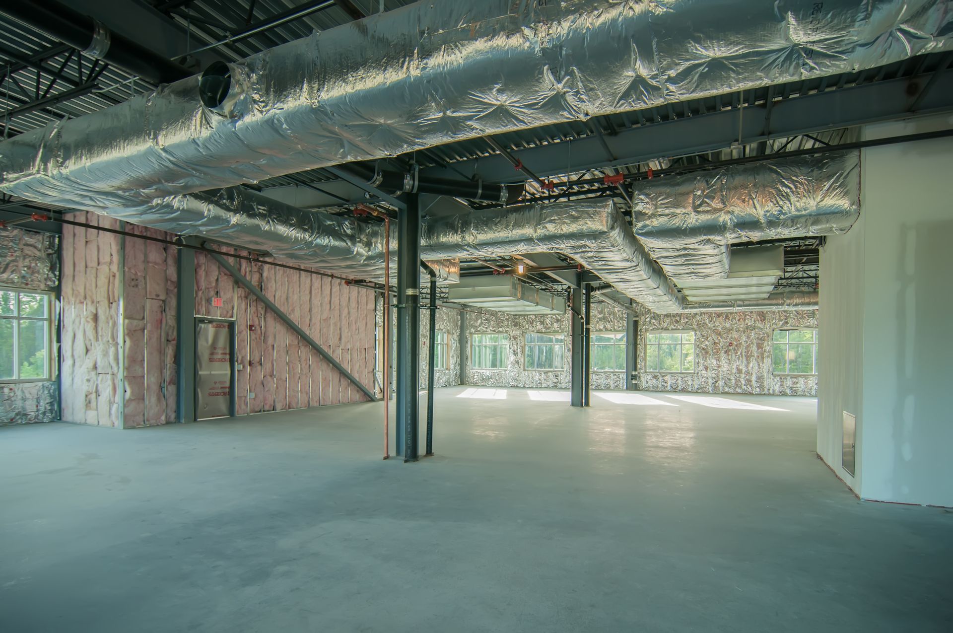 A large empty room with a lot of pipes coming out of the ceiling.