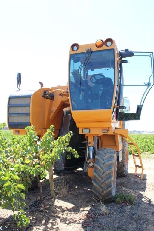 A yellow tractor is parked in a field with the door open