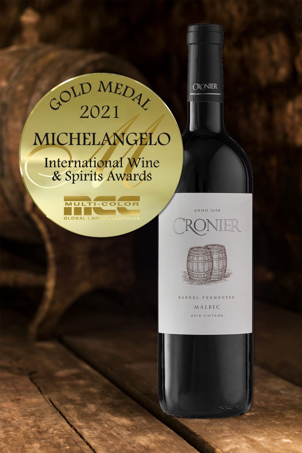 A bottle of wine with a gold medal on it is sitting on a wooden table.