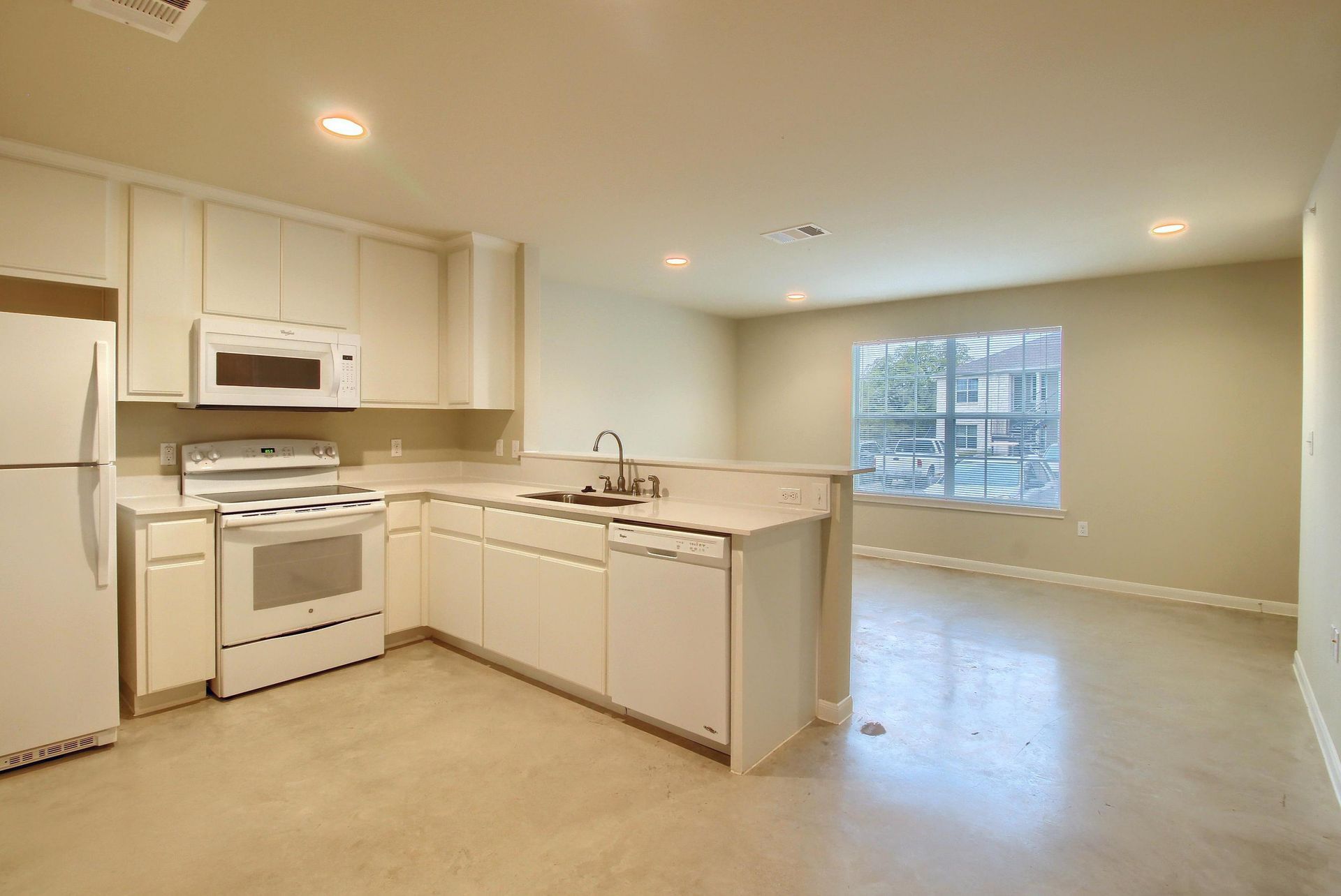 An empty kitchen with white cabinets and a refrigerator