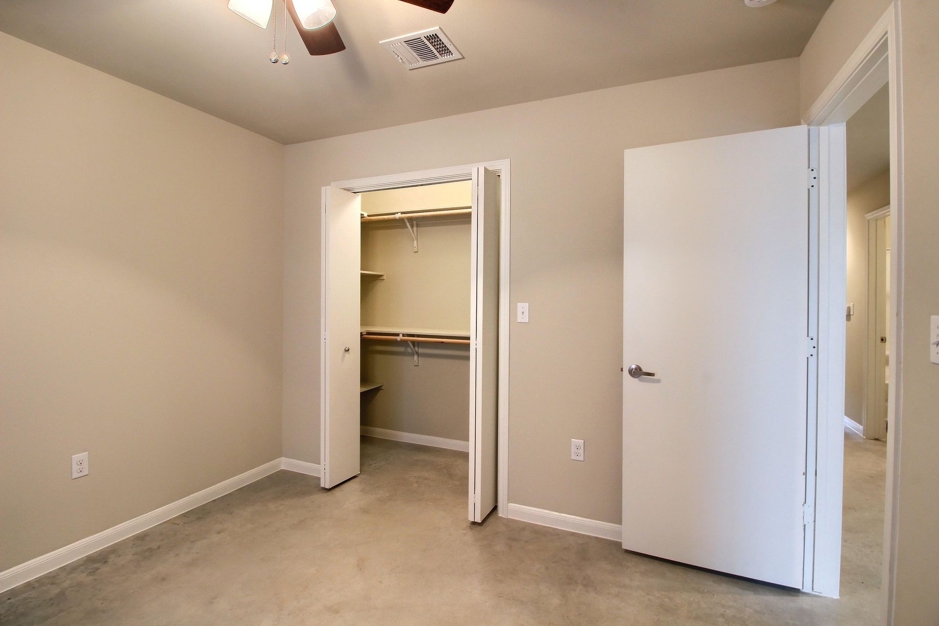 An empty bedroom with a walk in closet and a ceiling fan.