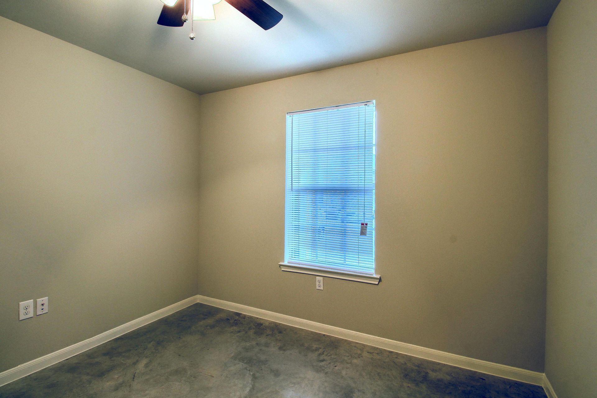 An empty room with a window and a ceiling fan
