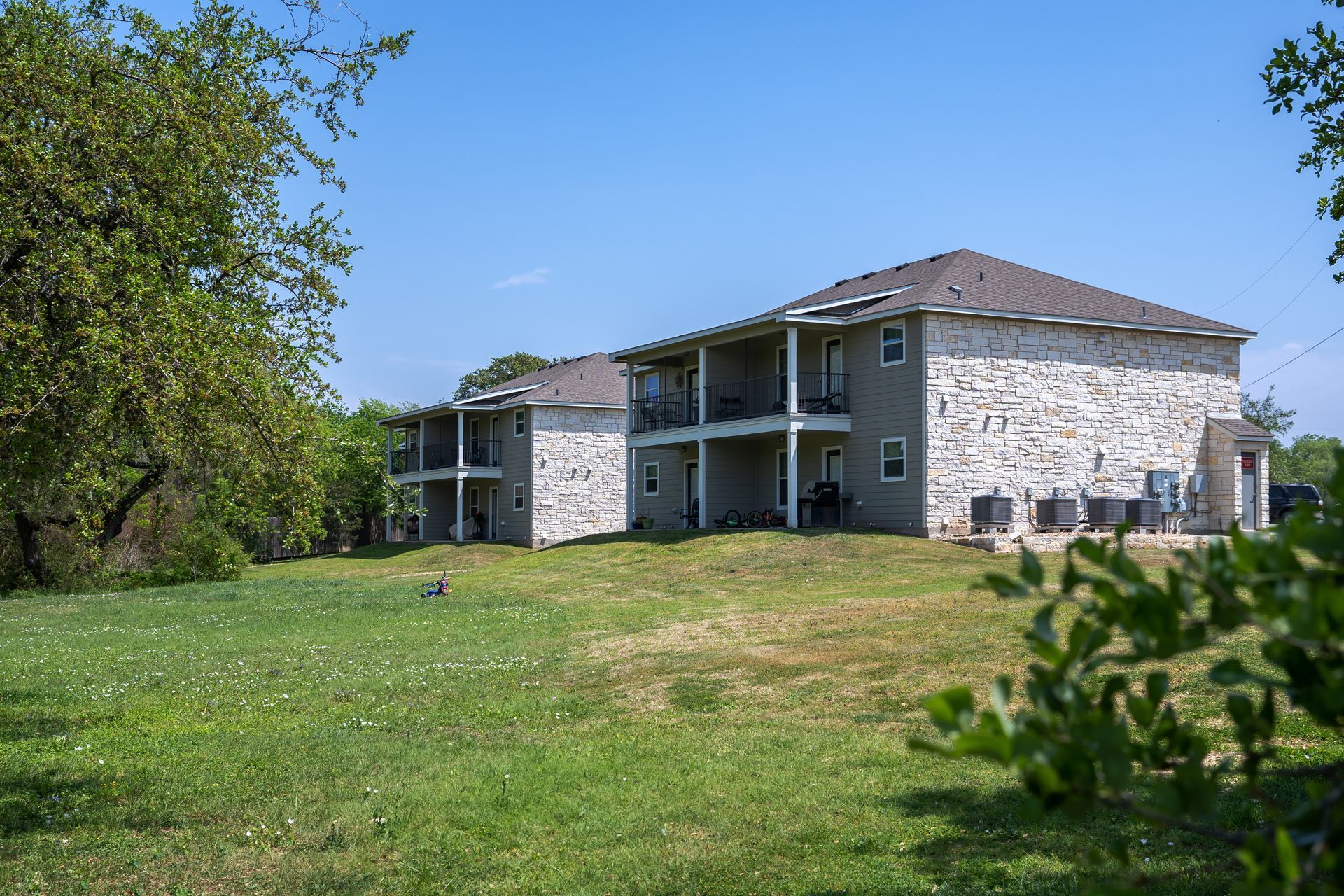 A large apartment building is sitting on top of a lush green field.