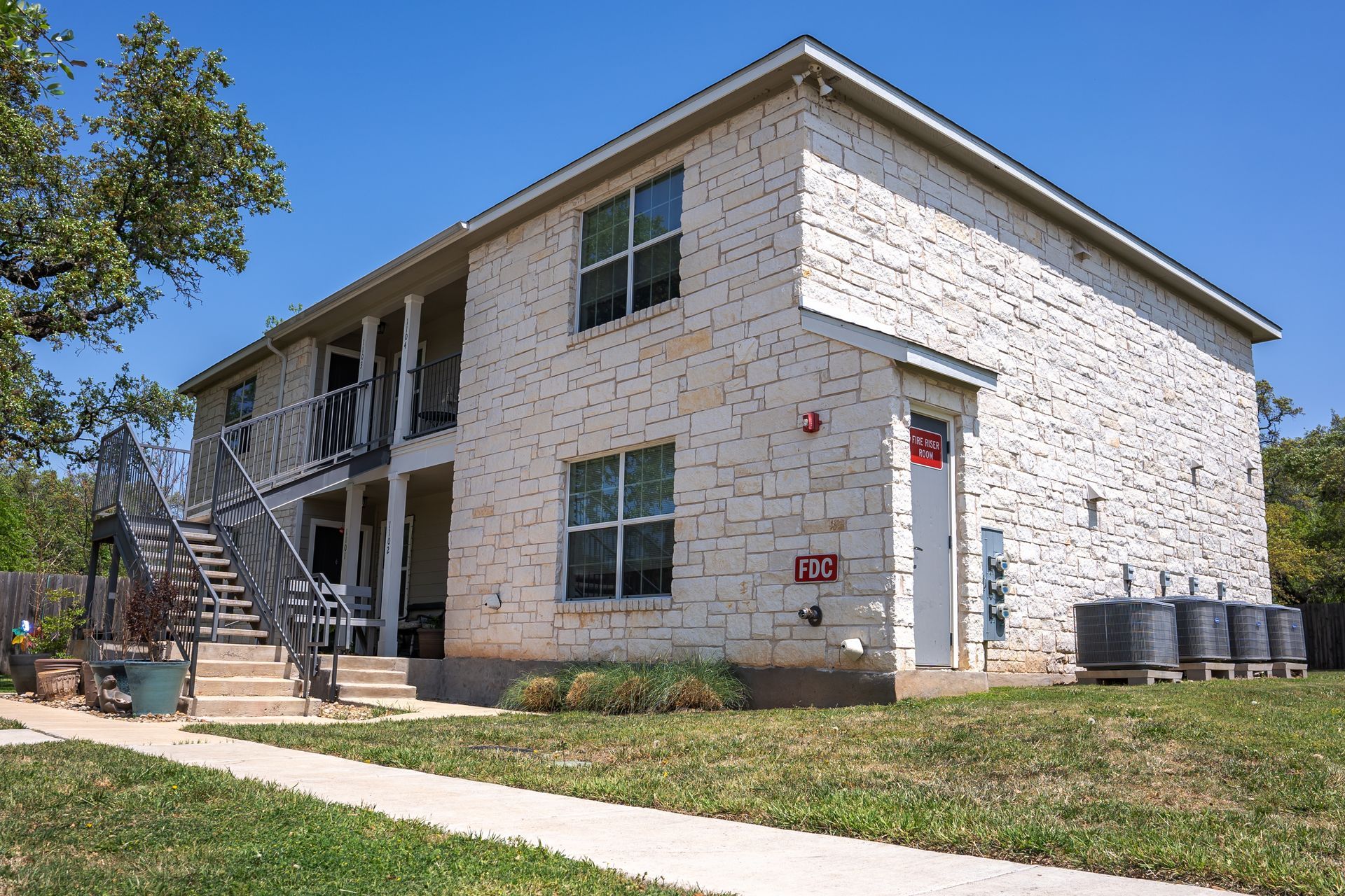 A white brick apartment building with stairs leading up to the second floor.