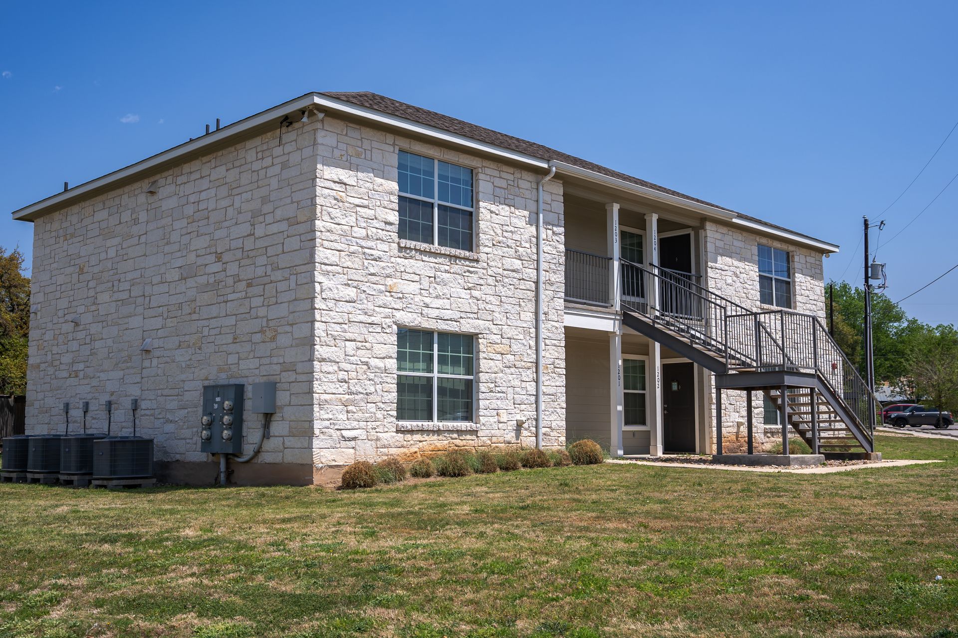 A large white brick apartment building with stairs leading up to the second floor.