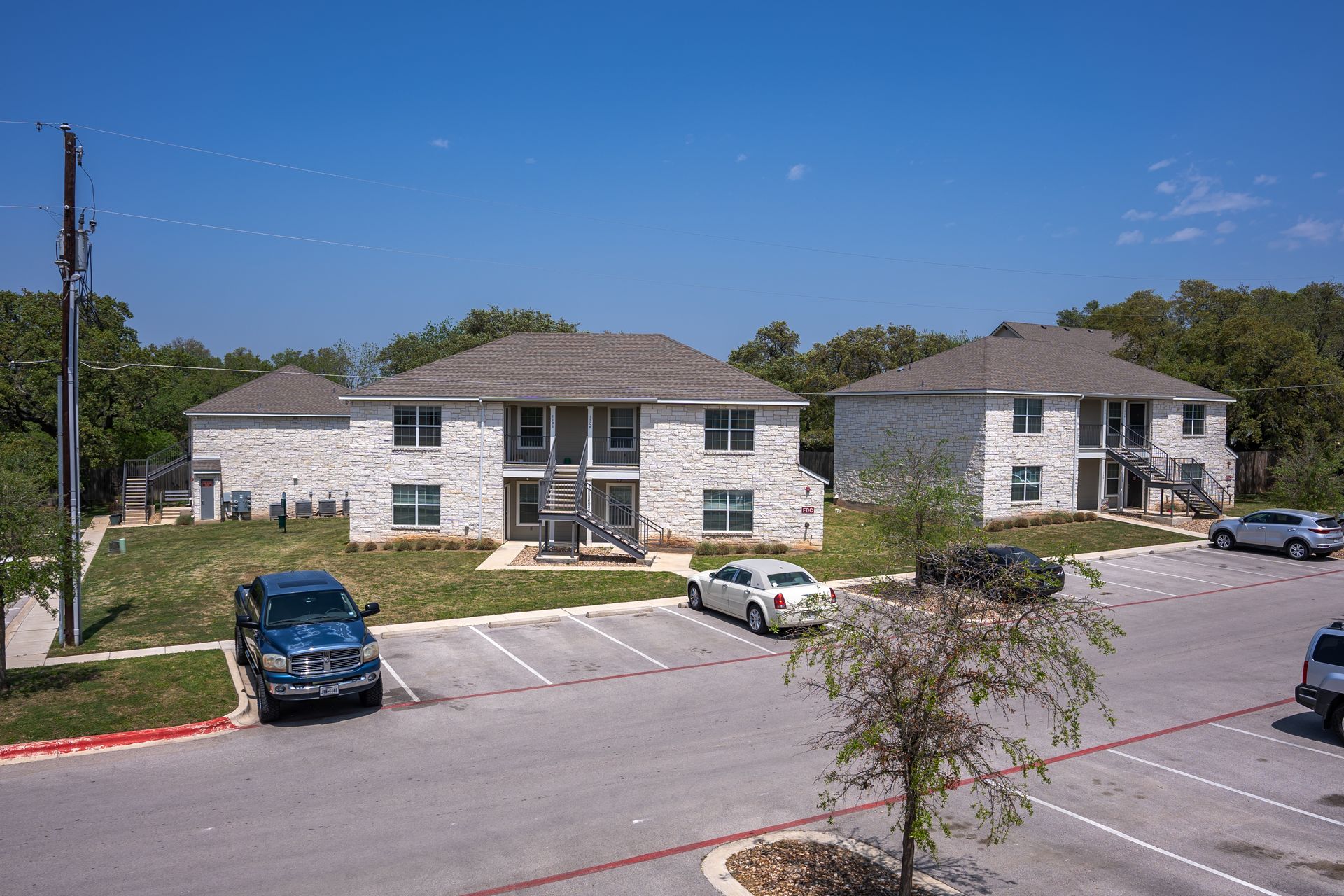 A group of apartments with cars parked in front of them.