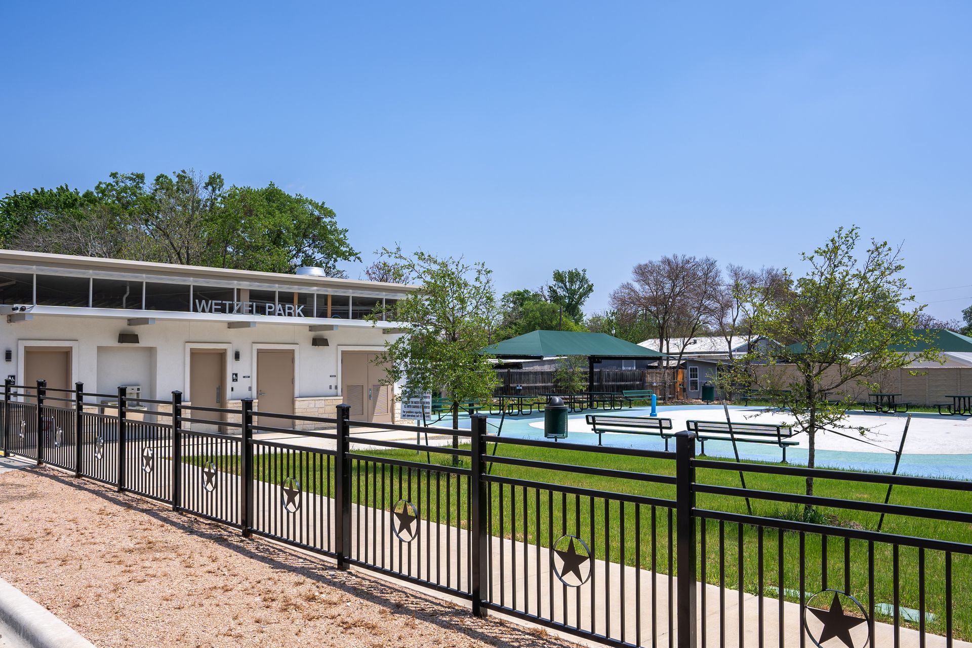 A black fence with stars on it surrounds a swimming pool.