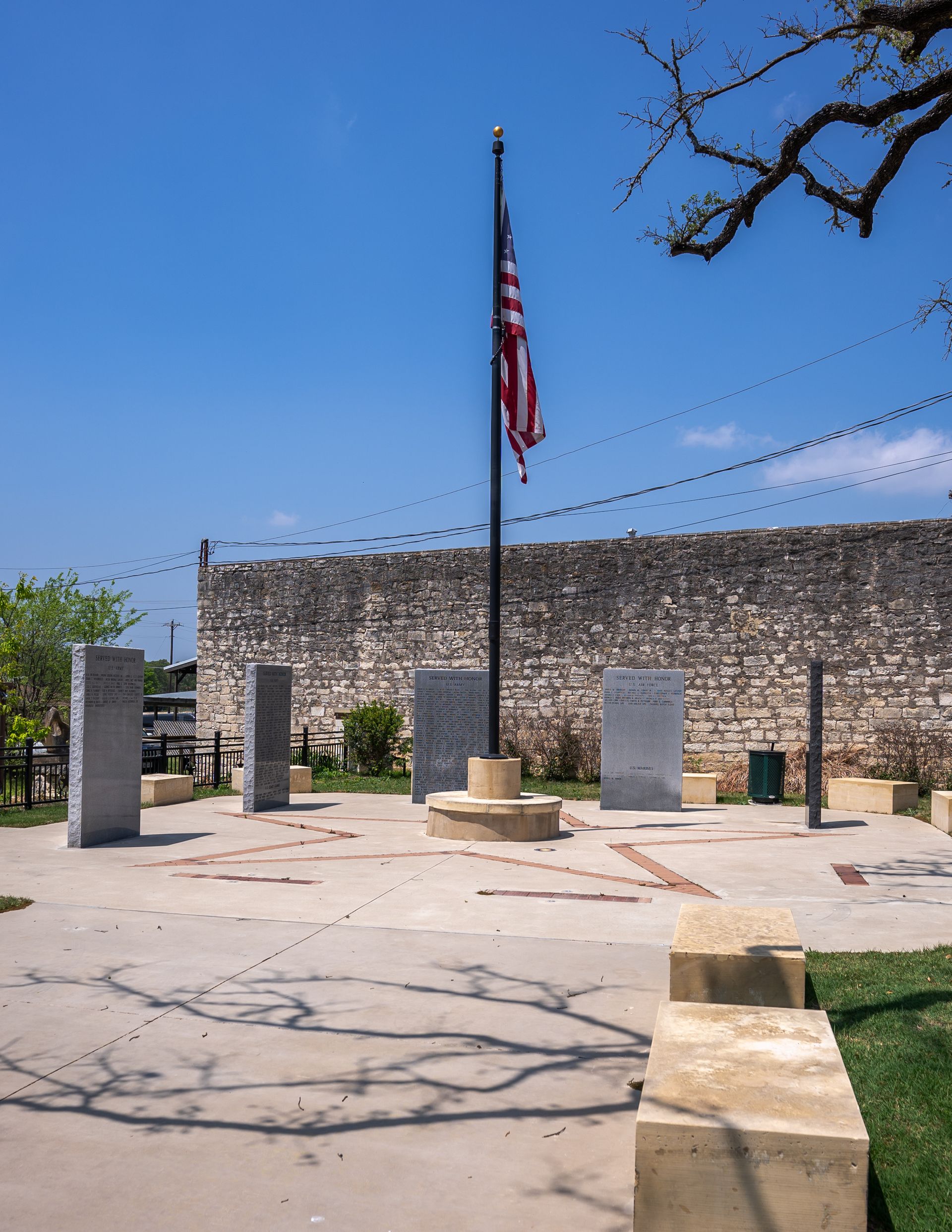 An american flag is flying in front of a stone wall.