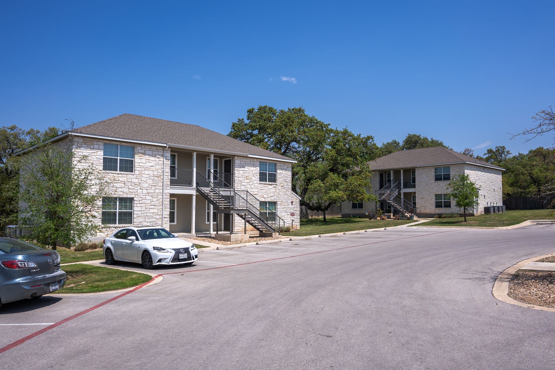 A white car is parked in front of a apartment building.