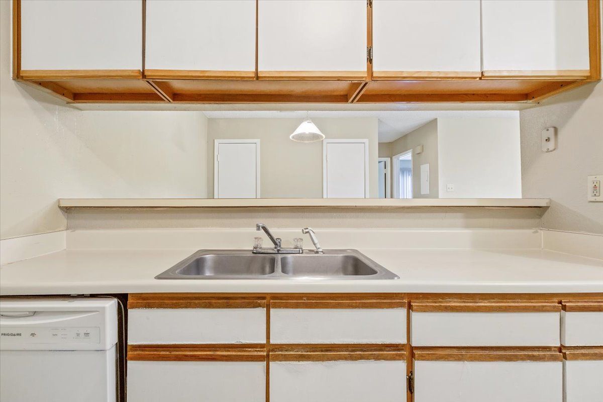 A kitchen with two sinks , a dishwasher , and white cabinets.