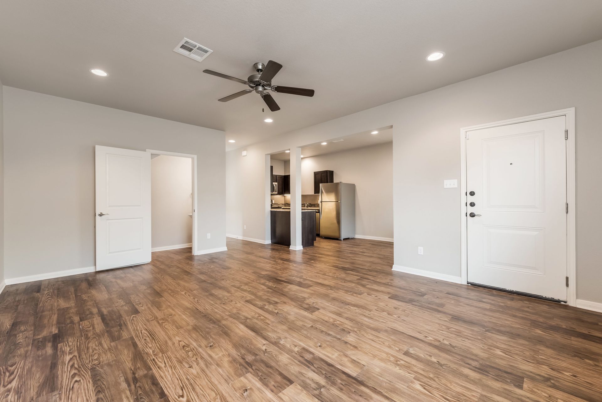 An empty living room with hardwood floors and a ceiling fan.