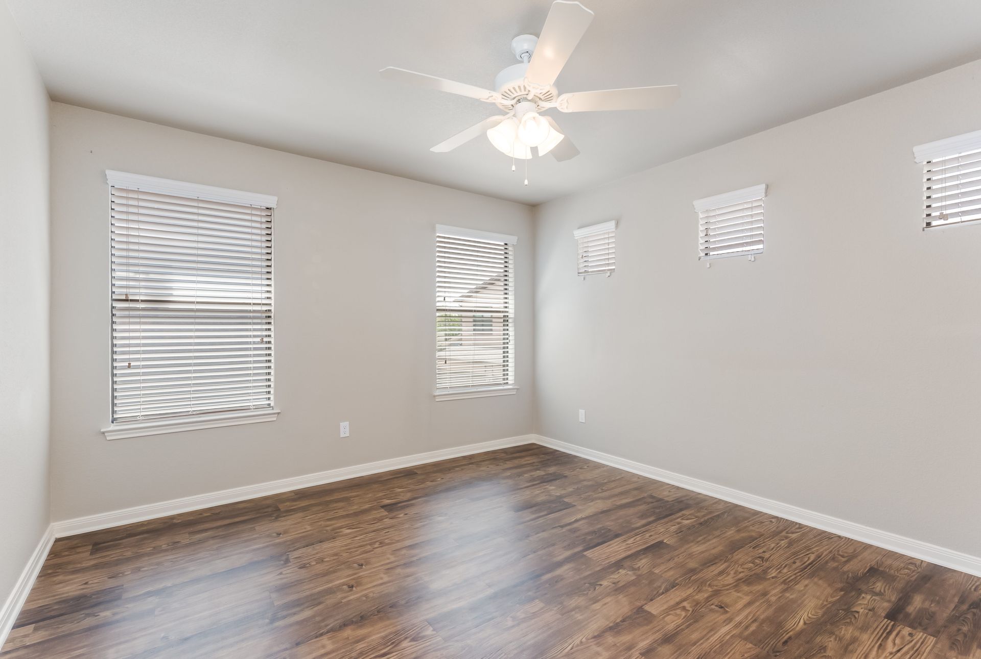 An empty bedroom with hardwood floors and a ceiling fan.