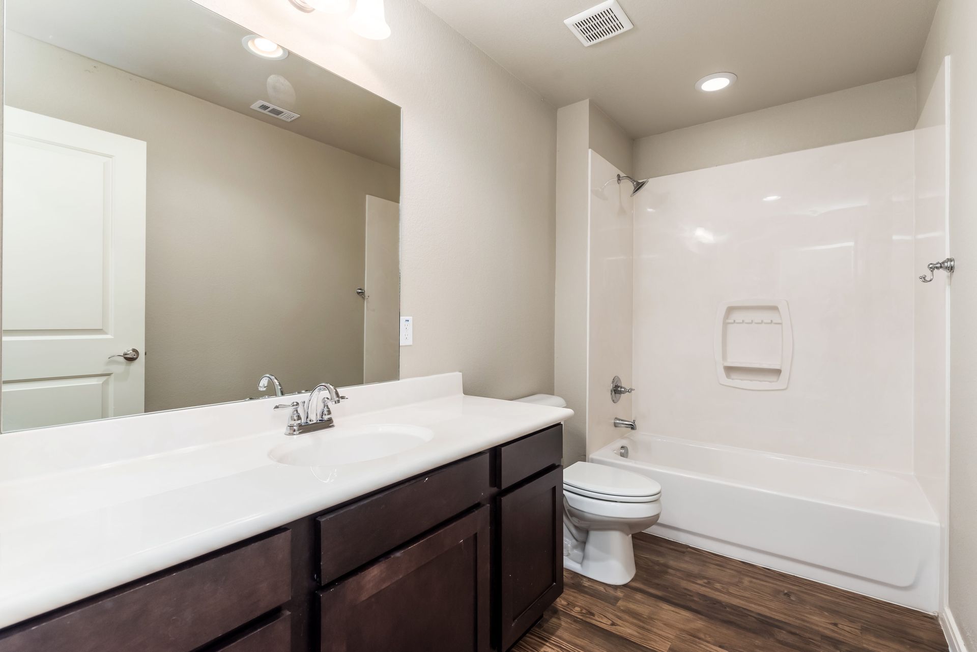 A bathroom with a sink , toilet , tub and mirror.