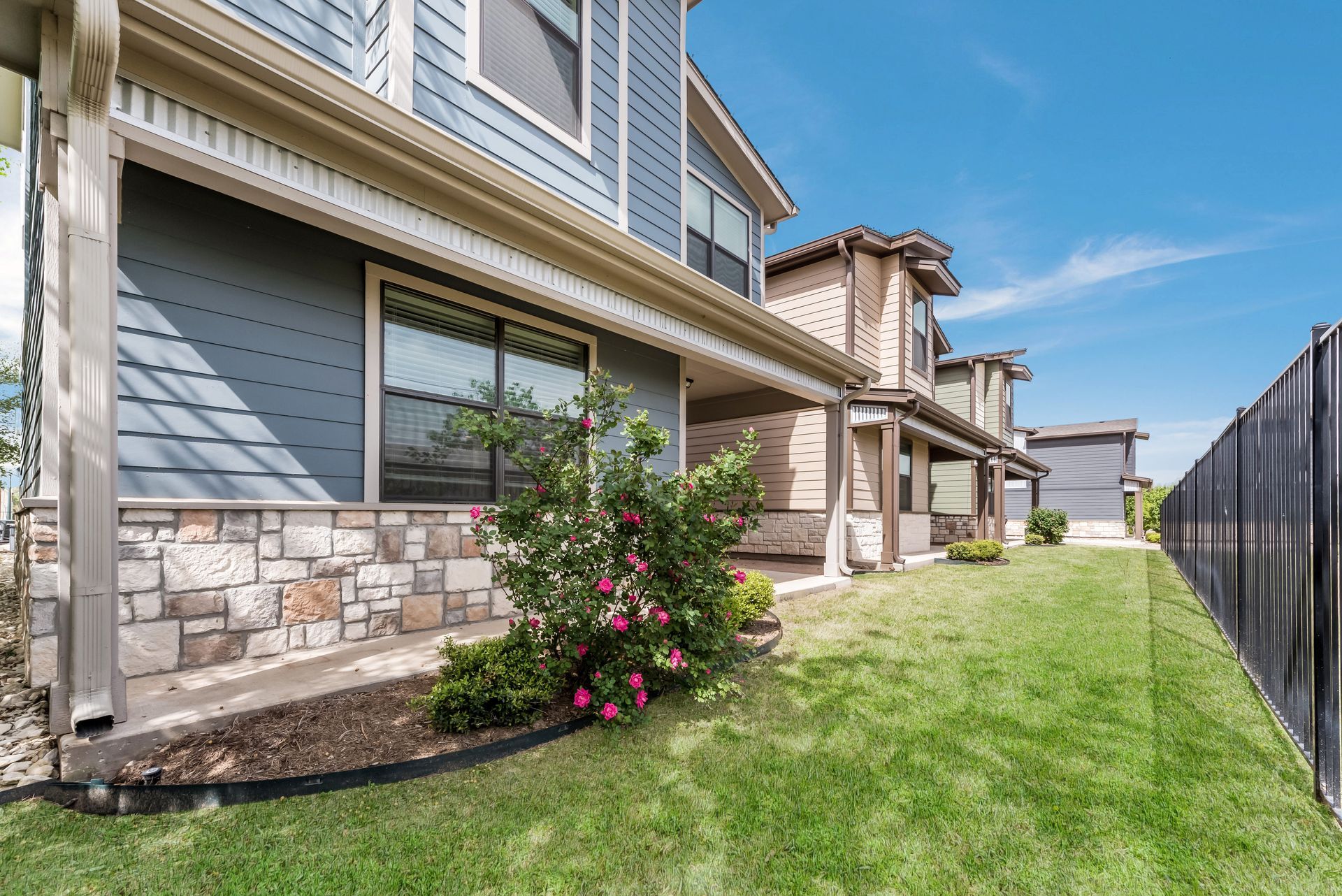 A row of houses with a large lawn in front of them.