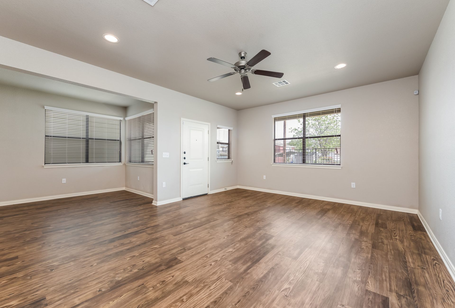 An empty living room with hardwood floors and a ceiling fan.