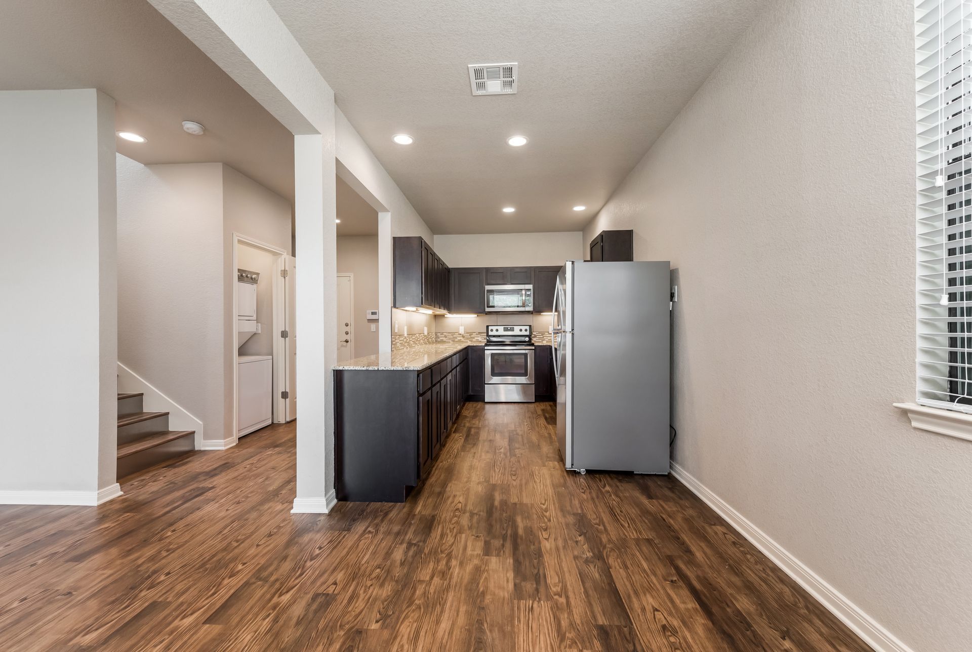 A kitchen with hardwood floors and a refrigerator in a house.