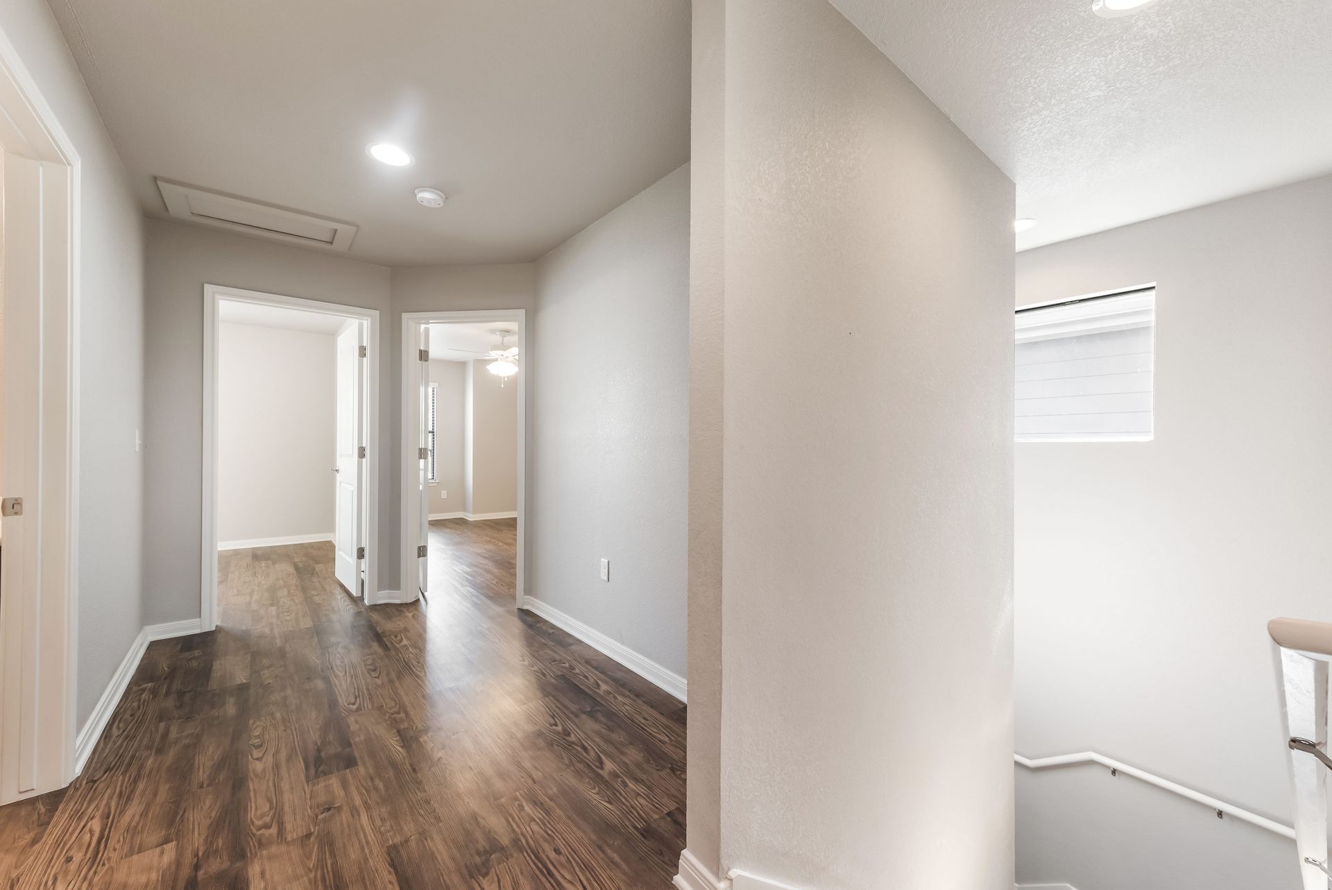 A hallway with hardwood floors and stairs in a house.