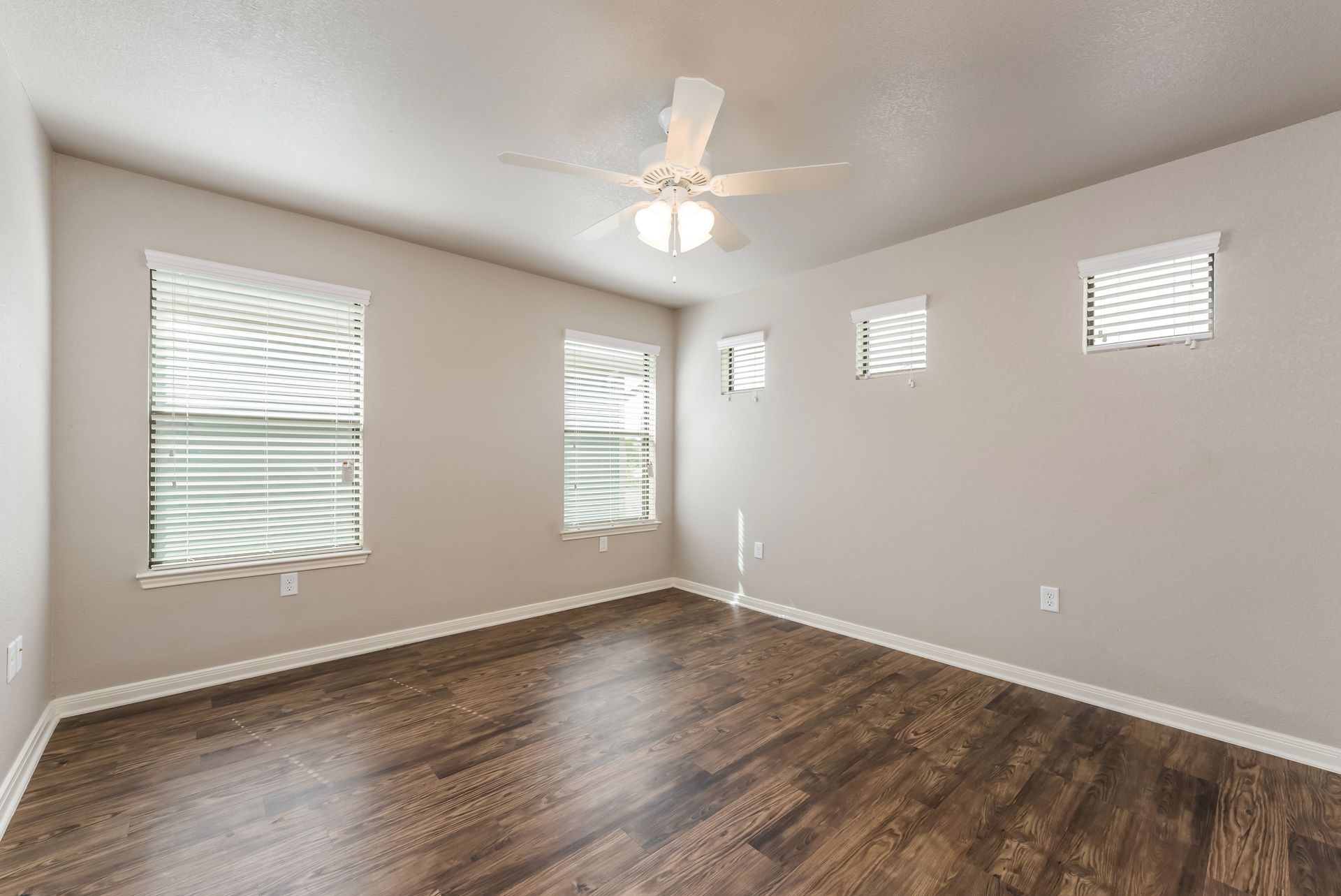 An empty bedroom with hardwood floors and a ceiling fan.