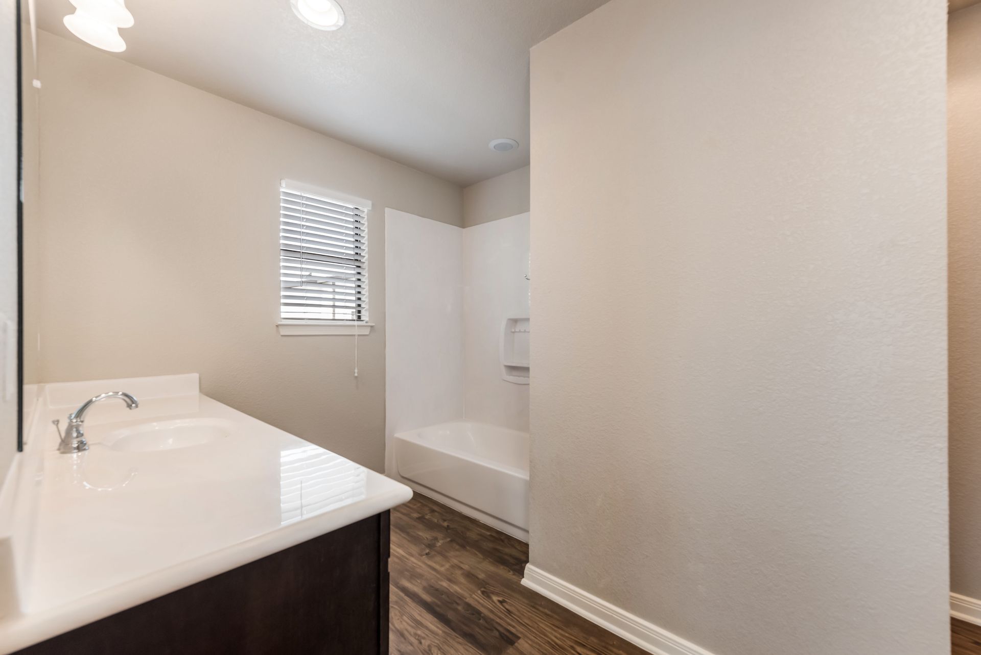 A bathroom with a sink , tub , mirror and window.