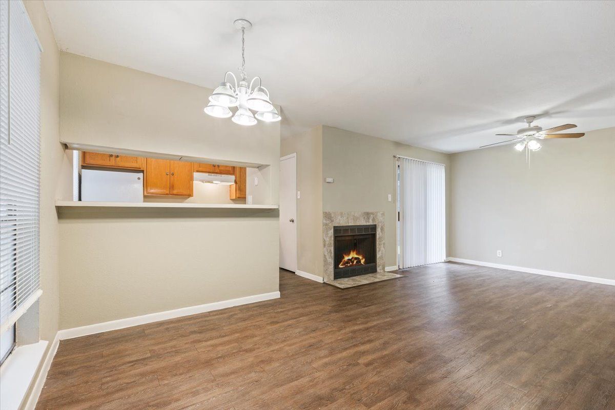 An empty living room with hardwood floors and a fireplace.