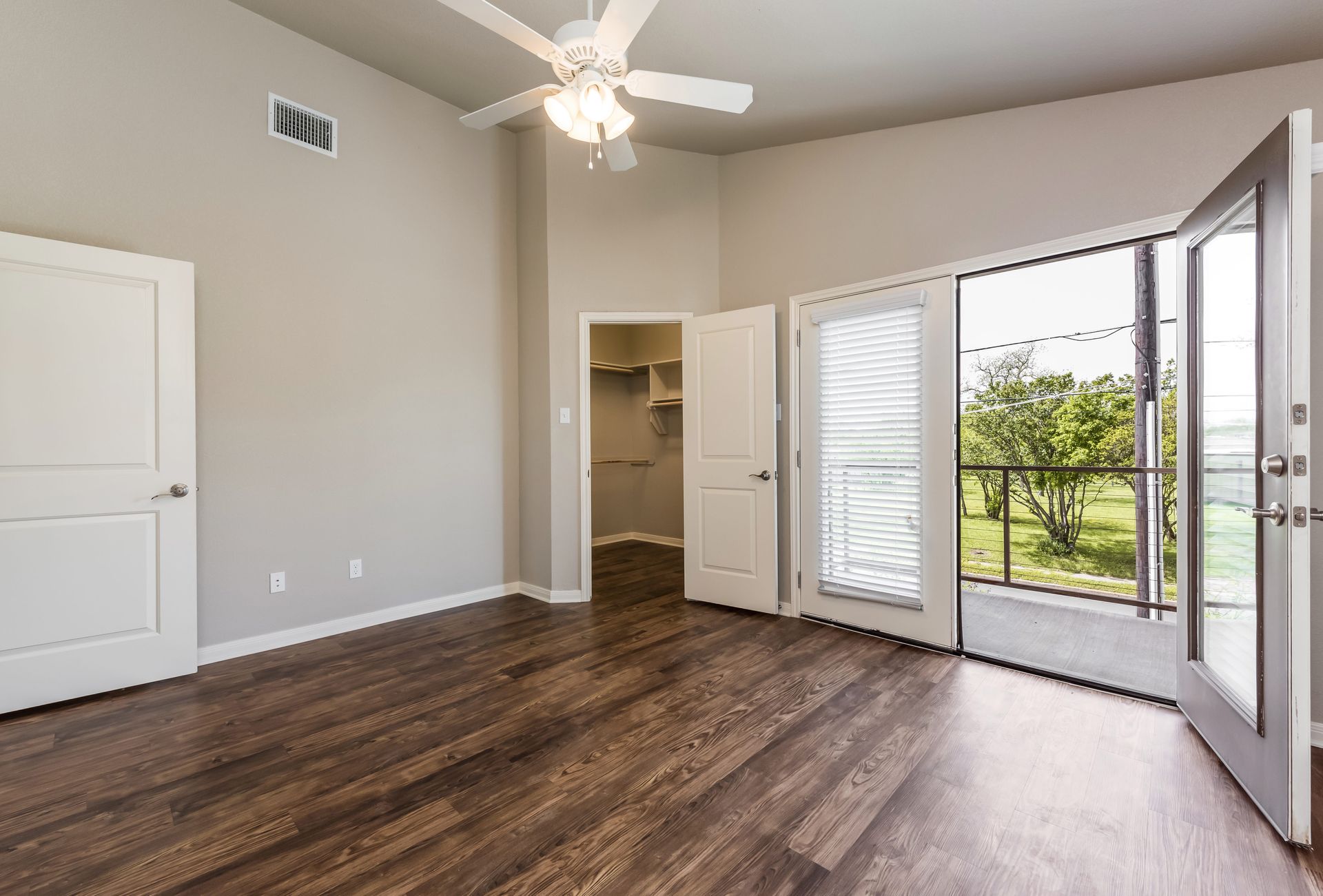 An empty room with hardwood floors and a ceiling fan.