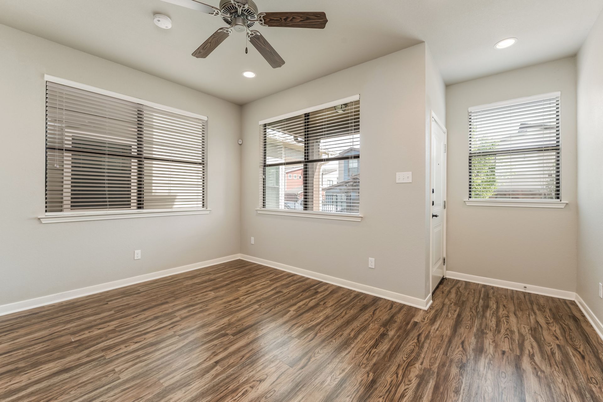 An empty living room with hardwood floors and a ceiling fan.